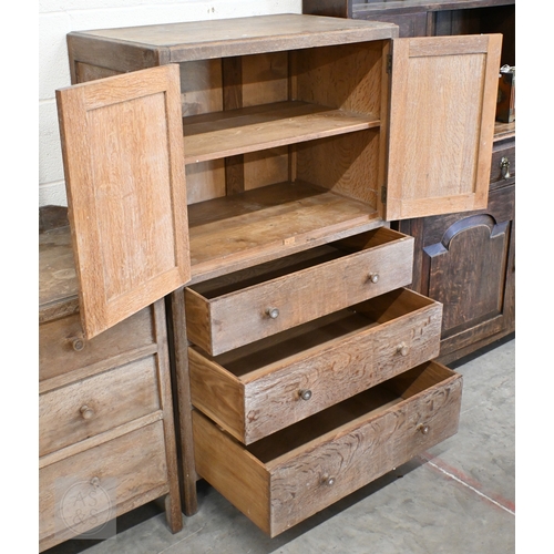 70 - Heal & Son, London - a limed oak cabinet with panelled cupboards over three drawers, ivorine pla... 