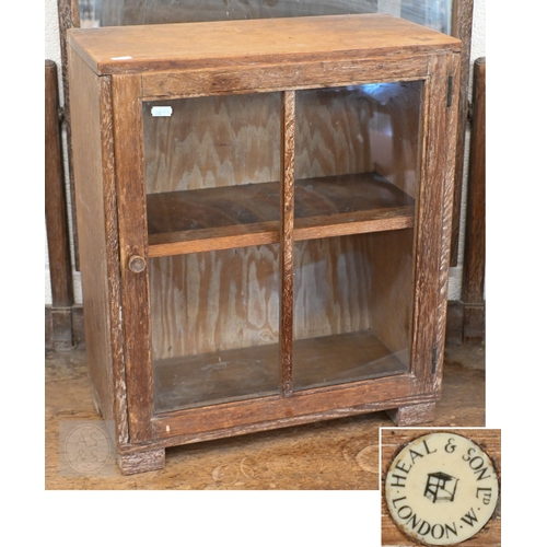 71 - Heal & Son, London - A small limed oak display cabinet with glazed door, standing on block feet,... 