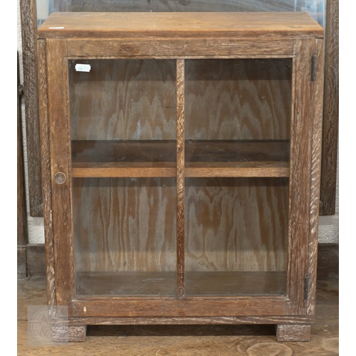71 - Heal & Son, London - A small limed oak display cabinet with glazed door, standing on block feet,... 