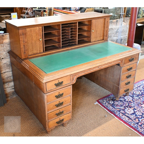 A large Arts & Crafts period oak twin pedestal desk, the raised superstructure with twin tambour doors over a green vinyl insert and ten drawers and recessed drawer, the verso with further drawers, 152 cm x 104 cm x 115 cm h oa//, the desktop 73 cm h
