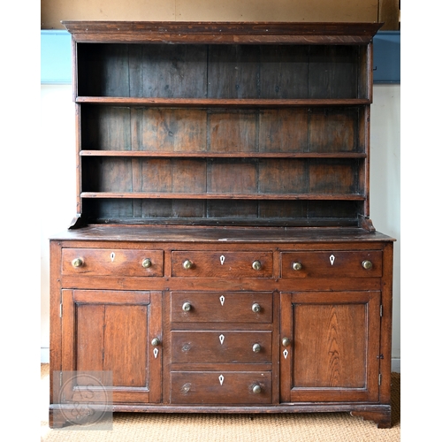 604 - An 18th century oak high dresser, the plank back open three tier rack over a base centred by four dr... 