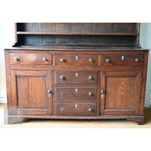 604 - An 18th century oak high dresser, the plank back open three tier rack over a base centred by four dr... 