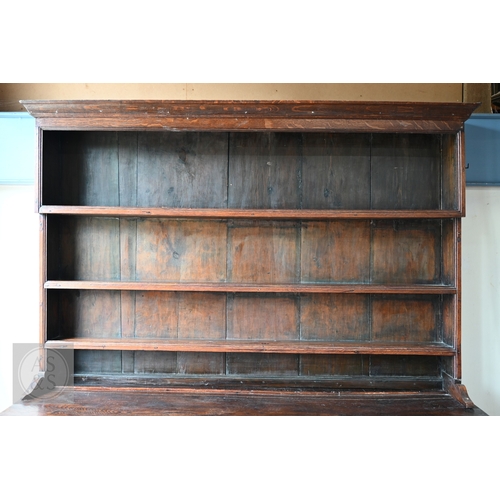 604 - An 18th century oak high dresser, the plank back open three tier rack over a base centred by four dr... 