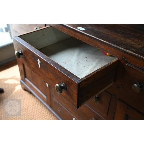 604 - An 18th century oak high dresser, the plank back open three tier rack over a base centred by four dr... 