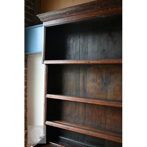 604 - An 18th century oak high dresser, the plank back open three tier rack over a base centred by four dr... 