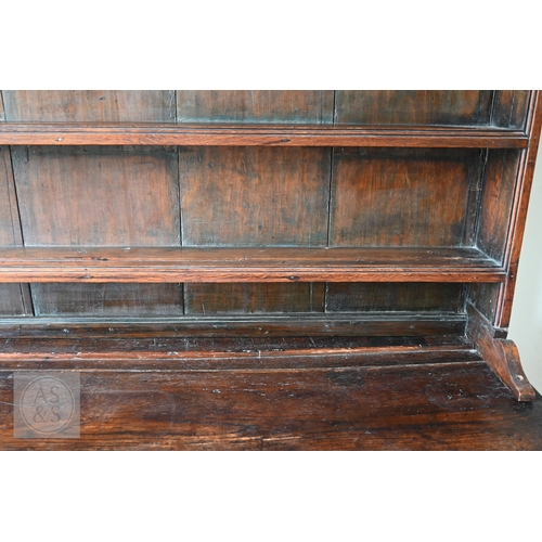 604 - An 18th century oak high dresser, the plank back open three tier rack over a base centred by four dr... 