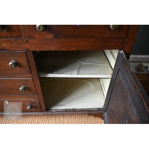 604 - An 18th century oak high dresser, the plank back open three tier rack over a base centred by four dr... 