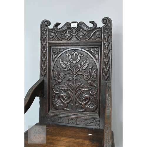 58 - An 19th century and later oak Wainscott armchair, the fielded back panel with twin dragons and folia... 
