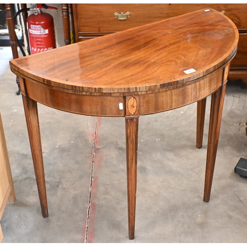 130 - A 19th century mahogany crossbanded demi-lune folding card table on moulded square tapering supports... 