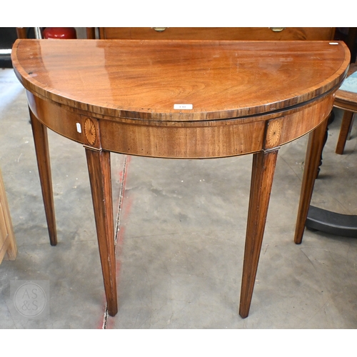 130 - A 19th century mahogany crossbanded demi-lune folding card table on moulded square tapering supports... 