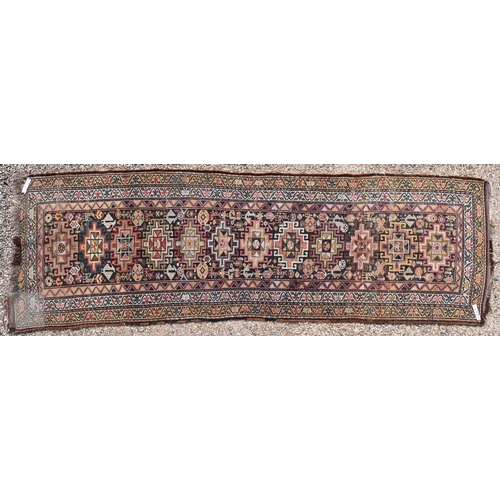 55 - An antique Caucasian Akstafa runner with vertically stacked eight-point star medallions on a dark fi... 