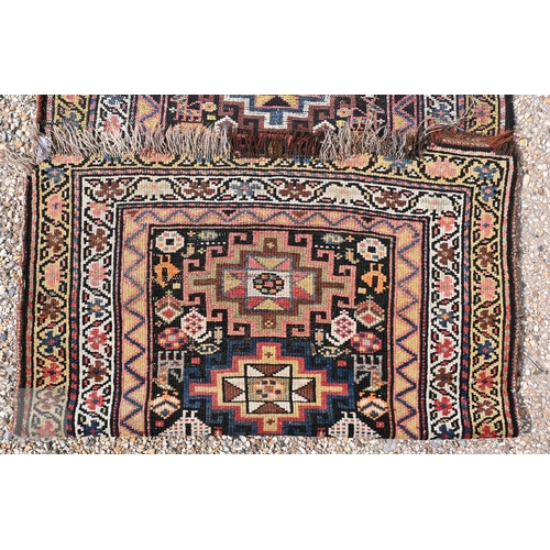 55 - An antique Caucasian Akstafa runner with vertically stacked eight-point star medallions on a dark fi... 