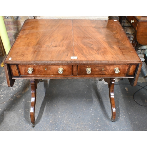 25 - A Victorian mahogany two drawer sofa table with drop ends raised on trestle ands and brass castors