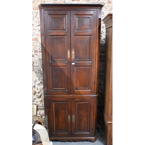 51 - A George III oak full height corner cupboard, the upper pair of triple framed panelled doors over tw... 