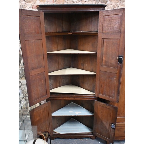 51 - A George III oak full height corner cupboard, the upper pair of triple framed panelled doors over tw... 