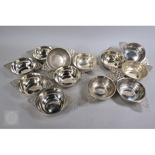 A set of twelve silver porringers, the twin pierced handles with vestigial gilding, maker HF, London 1928, 74oz (2313g), 12cm diameter approx