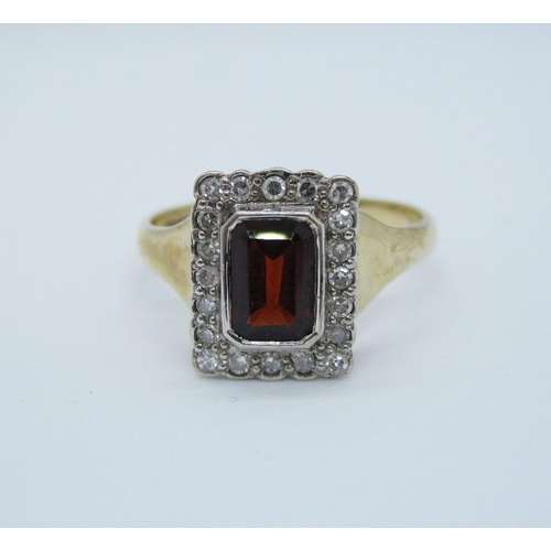 569 - A garnet and diamond Cluster Ring rub-over set step-cut garnet within frame of eight-cut diamonds in... 