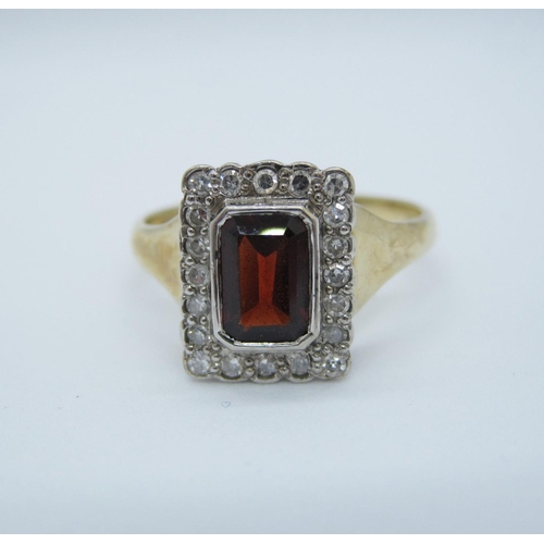 569 - A garnet and diamond Cluster Ring rub-over set step-cut garnet within frame of eight-cut diamonds in... 