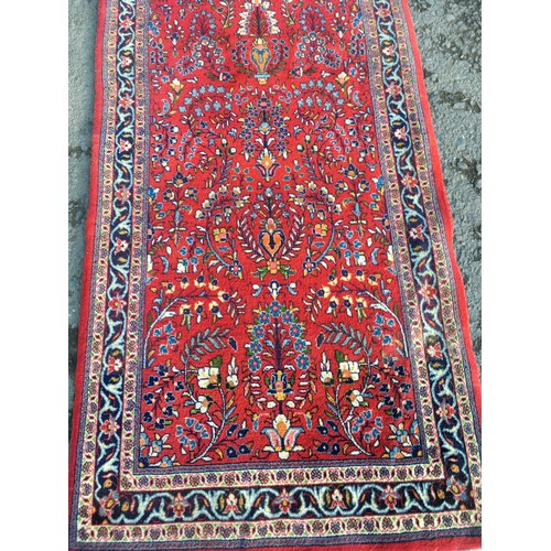 8 - A red ground Oriental Runner with trailing floral decoration within blue border 16ft 7in L x 3ft 4in... 