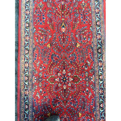 8 - A red ground Oriental Runner with trailing floral decoration within blue border 16ft 7in L x 3ft 4in... 