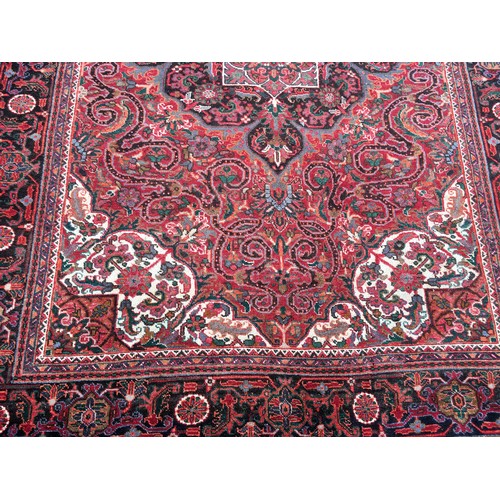 9 - A red ground Oriental woollen Rug with lotus flower central motif and stylised flower head border 9f... 