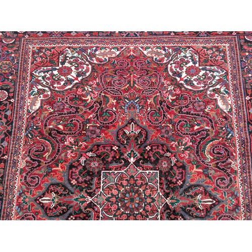 9 - A red ground Oriental woollen Rug with lotus flower central motif and stylised flower head border 9f... 