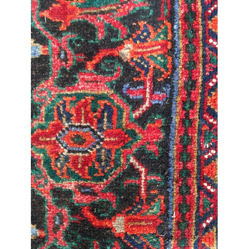 9 - A red ground Oriental woollen Rug with lotus flower central motif and stylised flower head border 9f... 