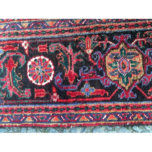 9 - A red ground Oriental woollen Rug with lotus flower central motif and stylised flower head border 9f... 