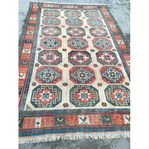 10 - A camel ground woollen Rug with three rows of medallions within border decorated stylised birds 11ft... 