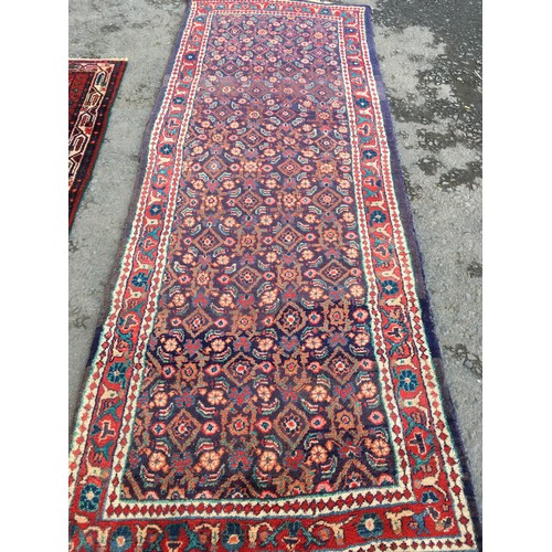 13 - A blue ground woollen Runner with floral decoration and red border 10ft L x3ft 8in W and a red groun... 