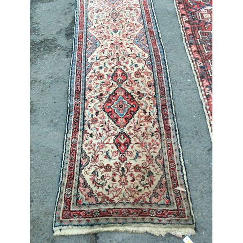 15 - A camel ground woollen Runner 14ft 4in L x 2ft 8in W and another red ground Runner with geometric de... 