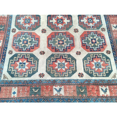 10 - A camel ground woollen Rug with three rows of medallions within border decorated stylised birds 11ft... 