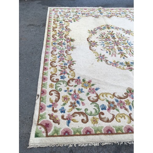 31 - A large cream Carpet with central oval of flowers within floral border, approx 13ft 10in L x 10ft 9i... 