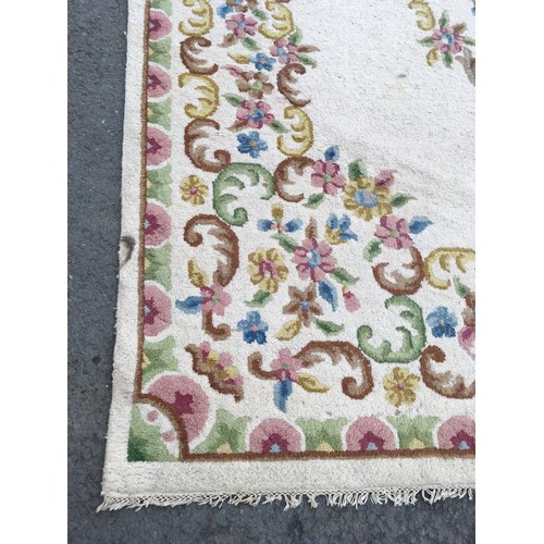 31 - A large cream Carpet with central oval of flowers within floral border, approx 13ft 10in L x 10ft 9i... 