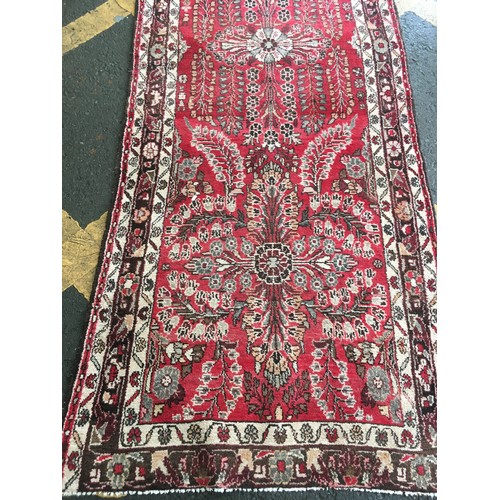 34 - A pink ground woollen Runner with stylised floral design within cream, red and brown multiple border... 