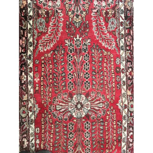 34 - A pink ground woollen Runner with stylised floral design within cream, red and brown multiple border... 