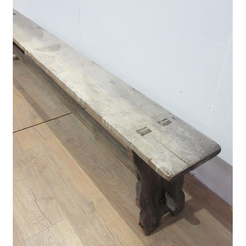 314 - A long pine Refectory Bench with shaped supports and stretchers, 8ft L x 10 1/2in W (one corner A/F)