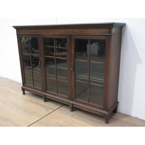 430 - A glazed oak three door Bookcase on turned supports, 5 ft W x 3 ft 7 in H x 14 in D.