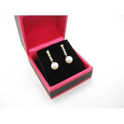 127 - A pair of Diamond and Cultured Pearl Earrings, each rubover and claw-set a line of five brilliant-cu... 