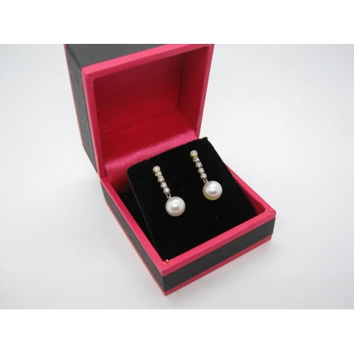 127 - A pair of Diamond and Cultured Pearl Earrings, each rubover and claw-set a line of five brilliant-cu... 