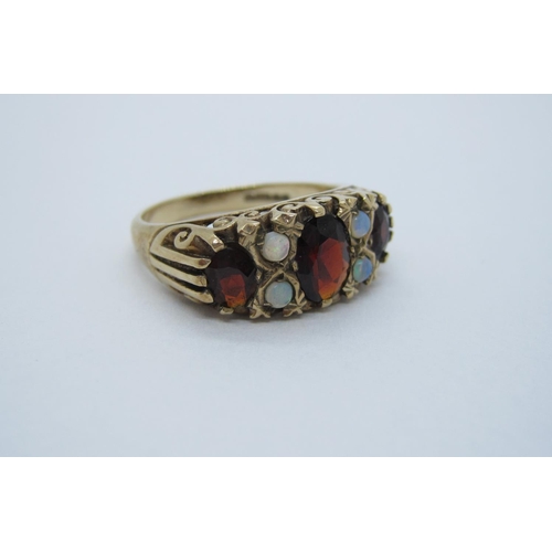 75 - A Garnet and Opal Ring, pave-set three graduated oval-cut garnets with pairs of round opals between,... 