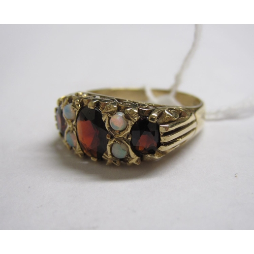 161 - A Garnet and Opal Ring pave-set three graduated oval-cut garnets with pairs of round opals between i... 