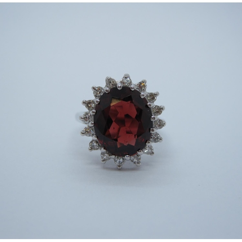 169 - A Garnet and Diamond Cluster Ring claw-set oval-cut garnet within a frame of eight-cut diamonds in w... 