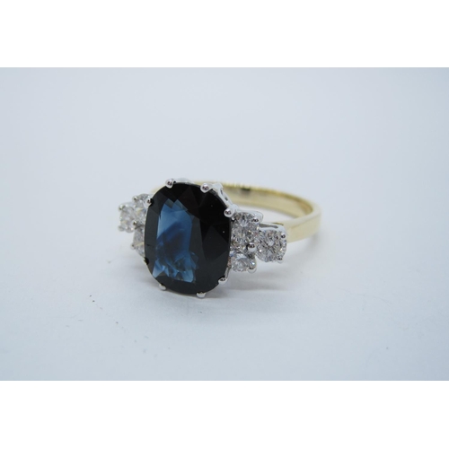 185 - A Sapphire and Diamond Ring claw-set oval-cut sapphire, 3.14cts, between trios of brilliant-cut diam... 