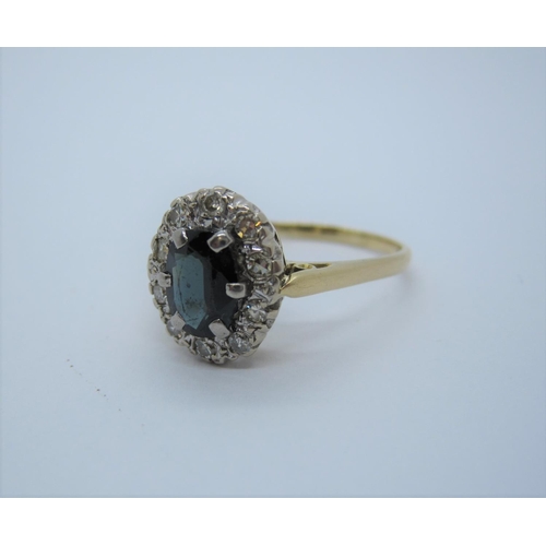 205 - A Sapphire and Diamond Cluster Ring claw-set oval-cut sapphire within a frame of illusion-set eight-... 