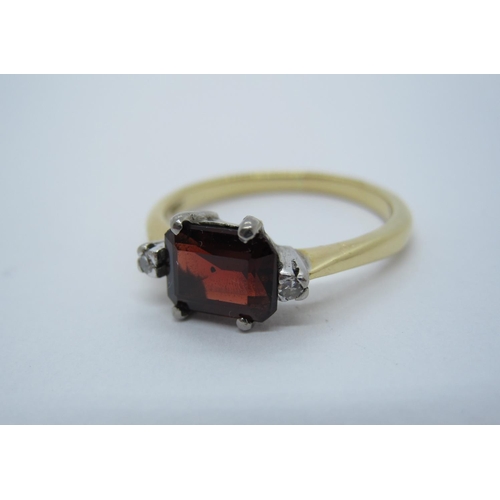 211 - A Garnet and Diamond Ring claw-set step-cut garnet between two eight-cut diamonds, stamped 18ct, rin... 