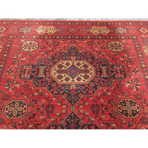 453 - A large red ground Rug with multi-geometric design borders, with three large central floral/geometri... 