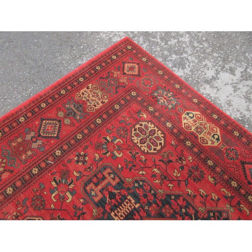 453 - A large red ground Rug with multi-geometric design borders, with three large central floral/geometri... 