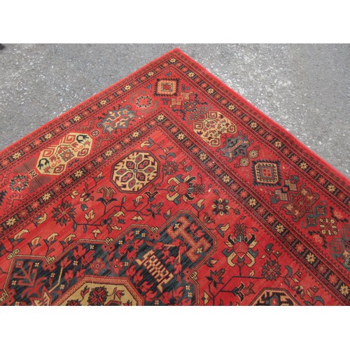 453 - A large red ground Rug with multi-geometric design borders, with three large central floral/geometri... 