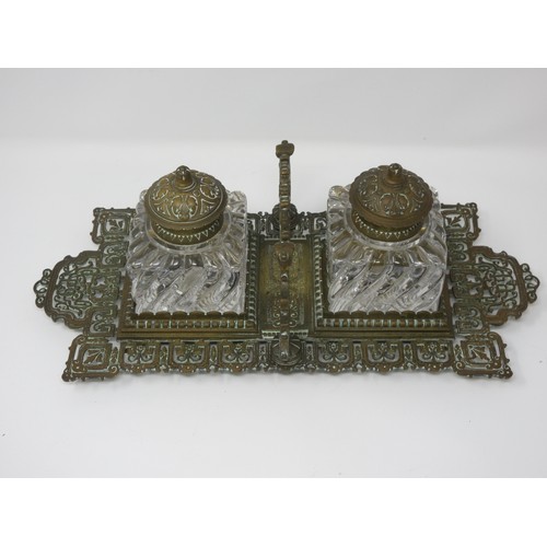 553 - A late 19th Century Aesthetic Movement brass double Inkstand with the brass lidded glass Inkwells on... 